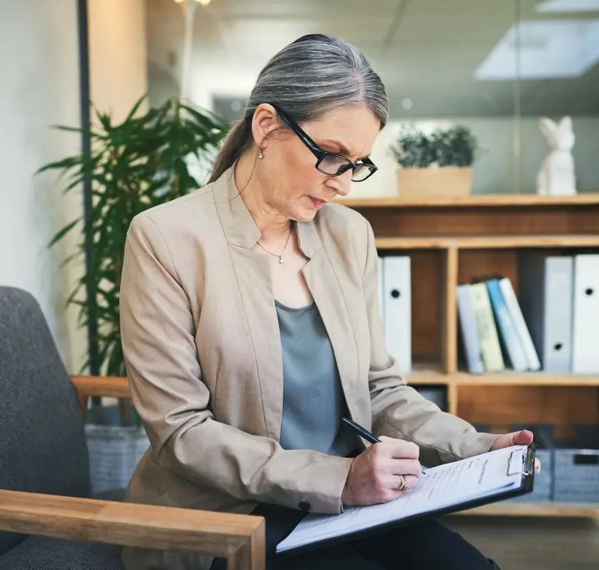 Shot of a mature psychologist writing notes on a clipboard
