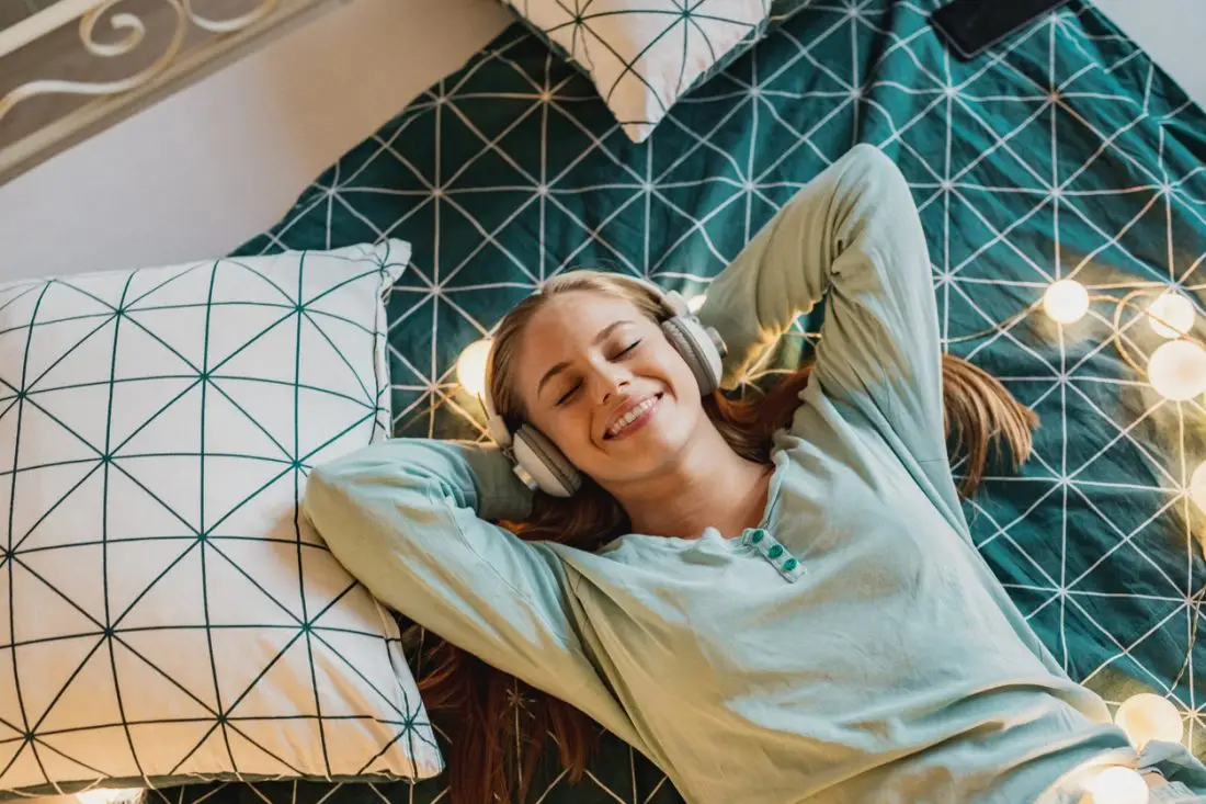 Young woman with headphones enjoying in bed